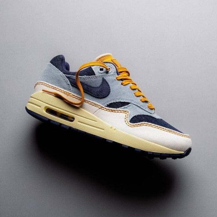 Sneaker zwevend boven neutrale achtergrond met duidelijk zicht op gestikte overlays, gestructureerde denim look en vintage-geïnspireerde kleurcombinatie