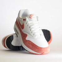 Sneaker balancerend op de hiel met zicht op de gebogen zoolvorm, roze suède en minimalistisch veterwerk