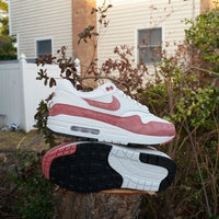 In scène gezette outdoorfoto met model op tuinmuur, sneaker valt op door het zachte kleurenpalet en streetwear vibe