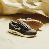 Beide sneakers gestyled op een gekreukte papieren ondergrond, met zicht op de veters, mudguard en off-white middenzool in natuurlijk licht
