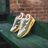 Streetstyle pose met twee sneakers op groene bank, volledige view op mudguard, gumsole en witte tonglabel in buitenlicht