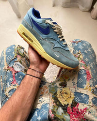 Bovenaanzicht van de Nike Air Max 1 PRM Dirty Denim – zicht op tonglabel, off-white veters en ruwe denim toebox via Snrkickz