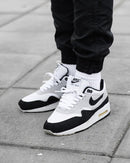 Nike Air Max 1 Essential White Pure Platinum Black – gedragen met grijze jogger en wit shirt voor een cleane streetwear fit