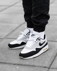 Nike Air Max 1 Essential White Pure Platinum Black – gedragen met grijze jogger en wit shirt voor een cleane streetwear fit