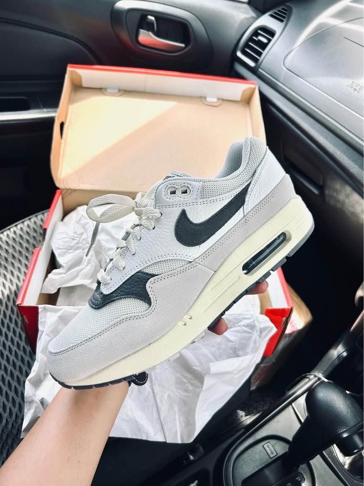 Flatlay van de Light Bone Iron Grey met originele box – strakke presentatie van een tijdloze Air Max 1 in rustige kleurstelling