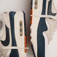 Gedetailleerd beeld van het stikselpatroon en grove texturen op de Air Max 1 Obsidian LX, met focus op materiaalcontrasten en branding