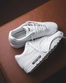 Sneaker HV1211-100 zwevend boven houten oppervlak gefotografeerd met zicht op transparante outsole, witte laces en snakeskin panelen