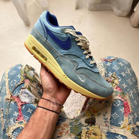 Bovenaanzicht van de Nike Air Max 1 PRM Dirty Denim – zicht op tonglabel, off-white veters en ruwe denim toebox via Snrkickz