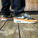 Detail van de Nike Air Max 1 Duck Anthracite focus op het geborduurde eendlogo en suède texturen via Snrkickz