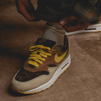 Bovenaanzicht van de Nike Air Max 1 Duck Pecan – zicht op tong, veters en opvallende oranje lining via Snrkickz