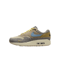 Close-up van de Safari Air Max 1 met grijze safari-panelen en blauwe Swoosh op witte achtergrond, ideaal voor mobile-first sneaker search