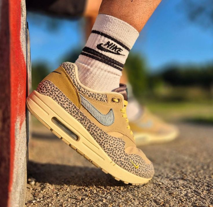 Nike Air Max 1 Safari on foot in daglicht met focus op contrast tussen de cobblestone mudguard en gele veters, gedragen met shorts