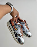 In hand shot van de Concepts Air Max 1 Heavy met zicht op corduroy toebox, flower Swoosh en contrasterende prints – premium afwerking met festival feel