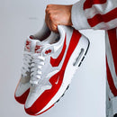 On-feet shot met rood-wit gestreepte broek, waarin de kleurblokken en het lage silhouet van de AM1 perfect tot z’n recht komen