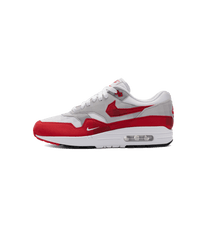 Nike Air Max 1 Low Poly in wit-rode colorway van de zijkant gefotografeerd, met cleane mudguard en transparante Air-unit voor een iconische look