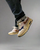 In-hand shot van de Nike Air Max 1 Tan Lines voor vrouwen met zichtbare texturen, zachte suède en summer-ready kleuren