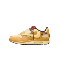 Zijaanzicht van de Travis Scott Air Max 1 in Wheat Lemon Drop colorway, met reversed Swoosh en hiking veters op een witte achtergrond