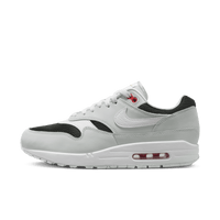 Zijaanzicht van de Nike Air Max 1 Urawa met zwart suède, zilveren mesh en een dieprode Swoosh, geïnspireerd op Japanse voetbalcultuur