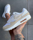 In-hand shot van de Nike Air Max 1 Sanddrift voor dames met zichtbare texturen, suède details en tonale afwerking