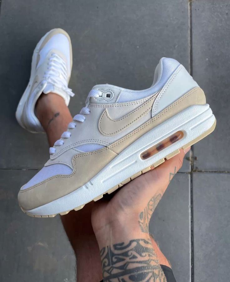 In-hand shot van de Nike Air Max 1 Sanddrift voor dames met zichtbare texturen, suède details en tonale afwerking
