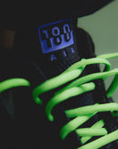 Close-up van de Nike Air Max 180 QS Joker FZ3058-001 met felgroene veters en reflecterende tong, gedetailleerde opname van het Nike Air 180-logo door Snrkickz.