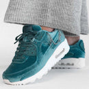 Zijaanzicht tijdens het lopen, sneaker aan voet met grijze broek, lichtreflectie op de ketting en upper zichtbaar