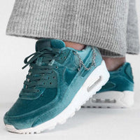 Zijaanzicht tijdens het lopen, sneaker aan voet met grijze broek, lichtreflectie op de ketting en upper zichtbaar