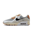 Zijaanzicht van de sneaker met grijze mesh, zwarte swoosh en crème details, tegen een witte achtergrond met oranje gumzool-accenten