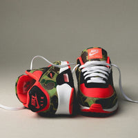 On feet van de Air Max 90 Reverse Duck Camo met opvallende rode upper, camouflagepanelen en zichtbare Air-unit