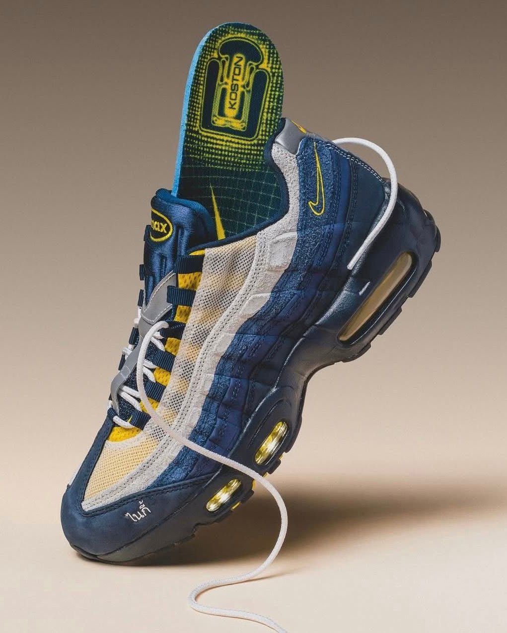 Close-up van de Nike Air Max 95 SB Eric Koston Obsidian Speed Yellow HQ8492-400 met geel stiksel en navy mesh, gefotografeerd in warme studioverlichting voor Snrkickz.
