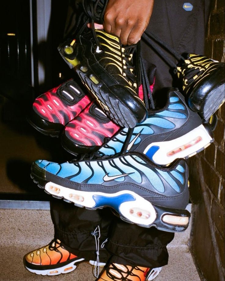 Nike Air Max Plus OG Hyper Blue DX0755-001 naast andere colorways, felblauwe details en gouden logo vallen op in groepsfoto, vastgelegd in urban setting door Snrkickz.