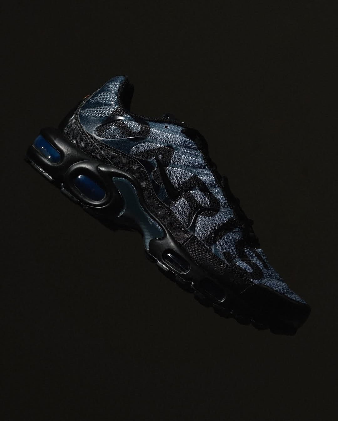Close-up van de Nike Air Max Plus PSG Paris Saint-Germain Black IB2253-001 met PSG-logo op de hiel, rode en blauwe details en strakke zwarte afwerking, exclusieve collab gefotografeerd door Snrkickz.