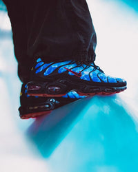 Nike Air Max Plus Shark Attack HQ3824-001 in paar gefotografeerd onder natuurlijk licht, donkerblauwe kleurtonen en reflecterende Tuned Air-units tonen het haaien-inspiratie design van Snrkickz.