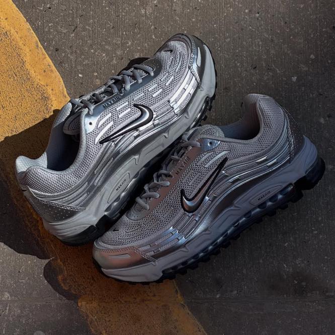 Flatlay van de TL 2.5 Metallic Silver sneaker bij een stoeprand, met metallic upper en zwarte Swoosh in warme belichting