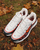 Nike Air Max TL 2.5 Phantom Total Orange FZ4110-001 gefotografeerd buiten op herfstbladeren, witte en oranje tinten contrasteren met de natuurlijke achtergrond, exclusief bij Snrkickz.