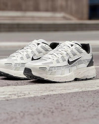 Nike P-6000 Platinum Tint Black gedragen op straat in daglicht, platinum tinten contrasteren met zwarte details, futuristische hardloopstijl gefotografeerd door Snrkickz.
