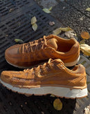 Close-up van de Nike P-6000 SE Flax Metallic Gold Sail HF0015-201 met suède textuur, glanzende gouden panelen en witte midsole, verfijnde premium details gefotografeerd door Snrkickz.