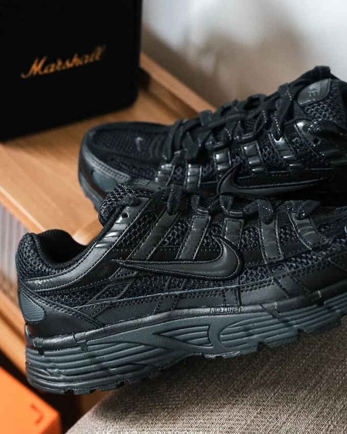 Nike P-6000 Triple Black FQ8732-010 gedragen met zwarte denim in een urban omgeving, monochrome look met reflecterende details vastgelegd door Snrkickz.