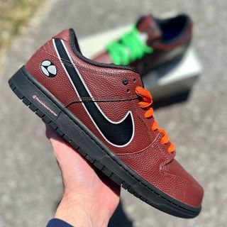 Sneaker in de hand, buiten gefotografeerd met een subtiel groen accent op de hiel zichtbaar in daglicht