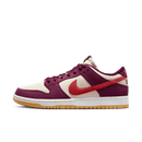 Zijaanzicht van de Skate Like a Girl x Nike SB Dunk Low Barely Rose DX4589-600 met roze suède upper, rode swoosh en geborduurde details