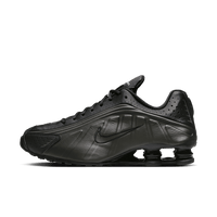 Studiofoto van de Nike Shox R4 Black Bright Crimson met zwarte upper, rode Shox demping en metallic zilveren details op de zijkant