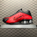 Close-up van de Shox-zool en mesh upper van de University Red R4, gefotografeerd tegen een metalen hek voor urban vibe