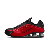 Zijaanzicht van de Nike Shox R4 in rood met zwarte details en metallic zilveren Shox-unit, tegen witte achtergrond