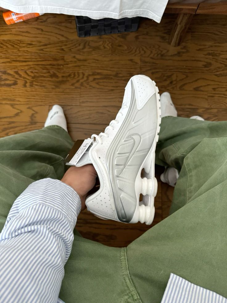 Casual shot van de Nike Shox R4 White Bright Crimson Metallic Silver binnenshuis met focus op metallic details