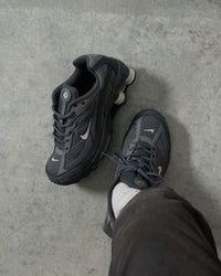 Sneaker on-feet met cargobroek en donkere vloer, focus op de demping en diepe grijstinten van de zool
