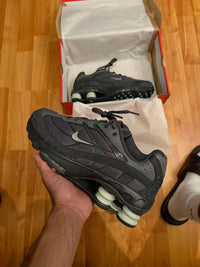 Close-up van de buitenzool en binnenvoering van de Nike Shox Ride 2 Anthracite, gefotografeerd op houten vloer met warme belichting