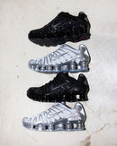 Twee paar Chrome Nike Shox TL sneakers naast elkaar op witte ondergrond, met zicht op glanzende details en zoolstructuur