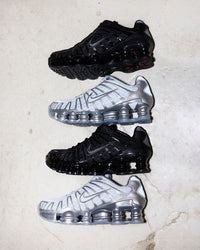 Twee paar Chrome Nike Shox TL sneakers naast elkaar op witte ondergrond, met zicht op glanzende details en zoolstructuur