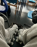 Streetwear-look met Chrome Shox TL aan voeten, benen gestrekt over treinstoel met zilveren details zichtbaar in natuurlijk licht