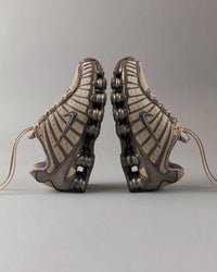 Nike Shox TL Khaki Achteraanzicht van de Nike Shox TL Khaki Ironstone Off Noir, waarbij de donkere zool en iconische Shox technologie centraal staan Off Noir